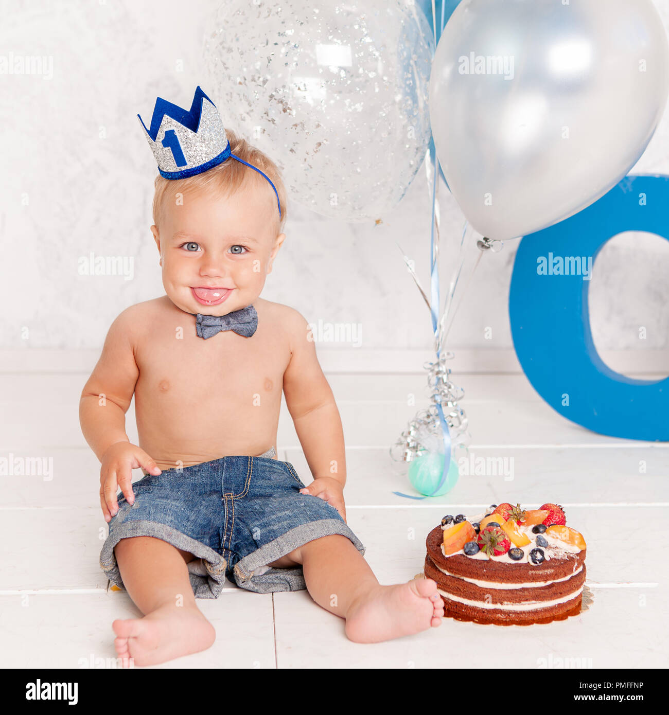 Portrait von Fashion lustige kleine Junge im Studio mit großen blauen Buchstaben, Luftballons und Kuchen. Konzept Feier Stockfoto