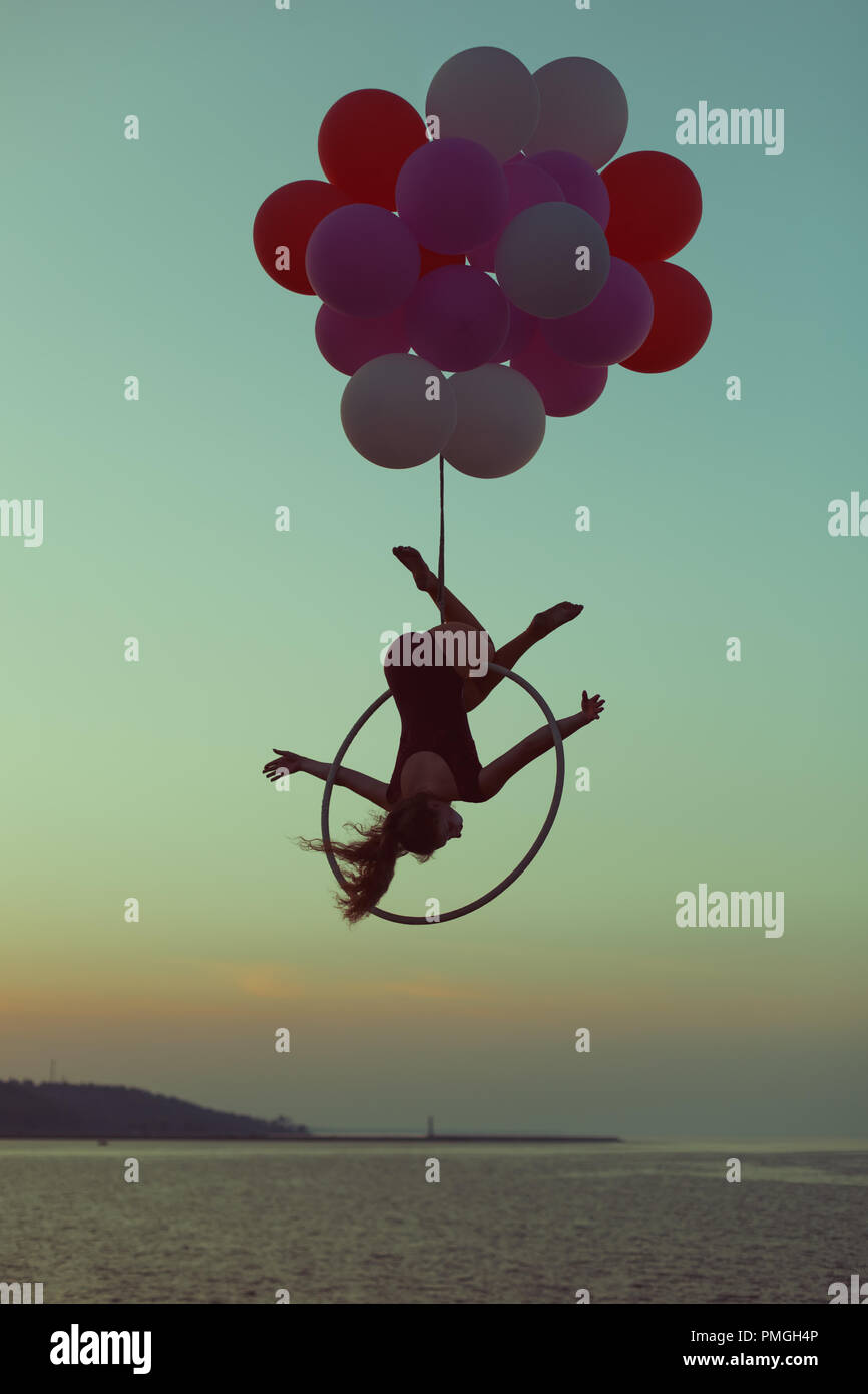 Mädchen Acrobat funktioniert Tricks in der Luft auf einem Kreis und Luftballons. Stockfoto