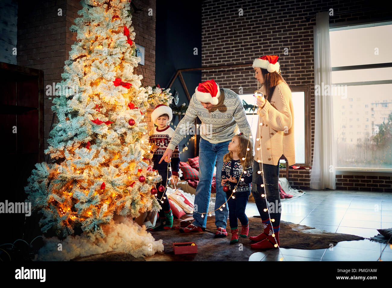Eine glückliche Familie schmückt den Weihnachtsbaum zu Hause. Stockfoto