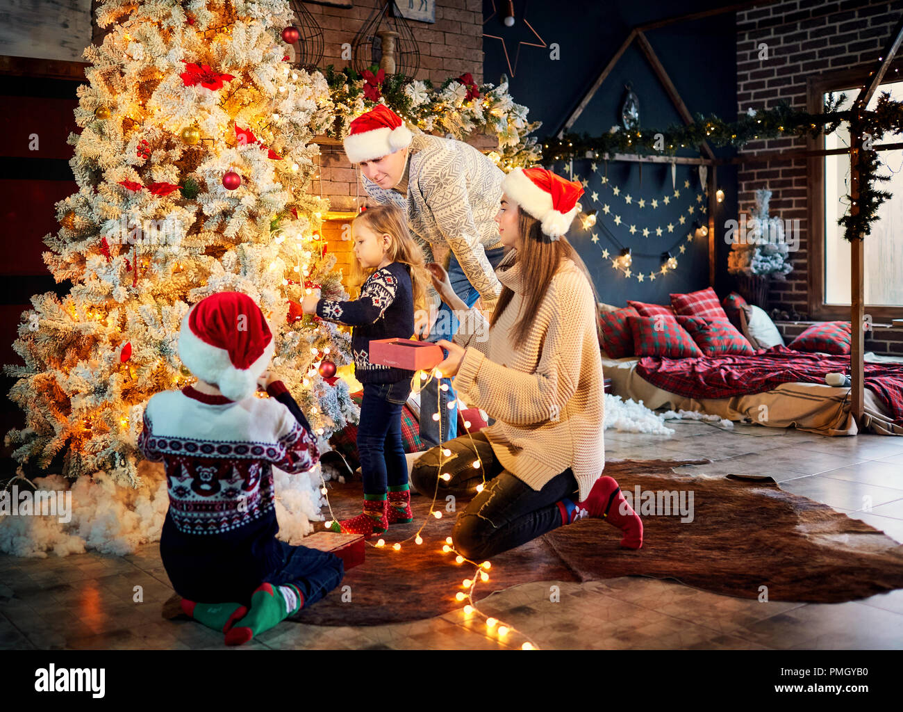 Eine glückliche Familie schmückt den Weihnachtsbaum zu Hause. Stockfoto