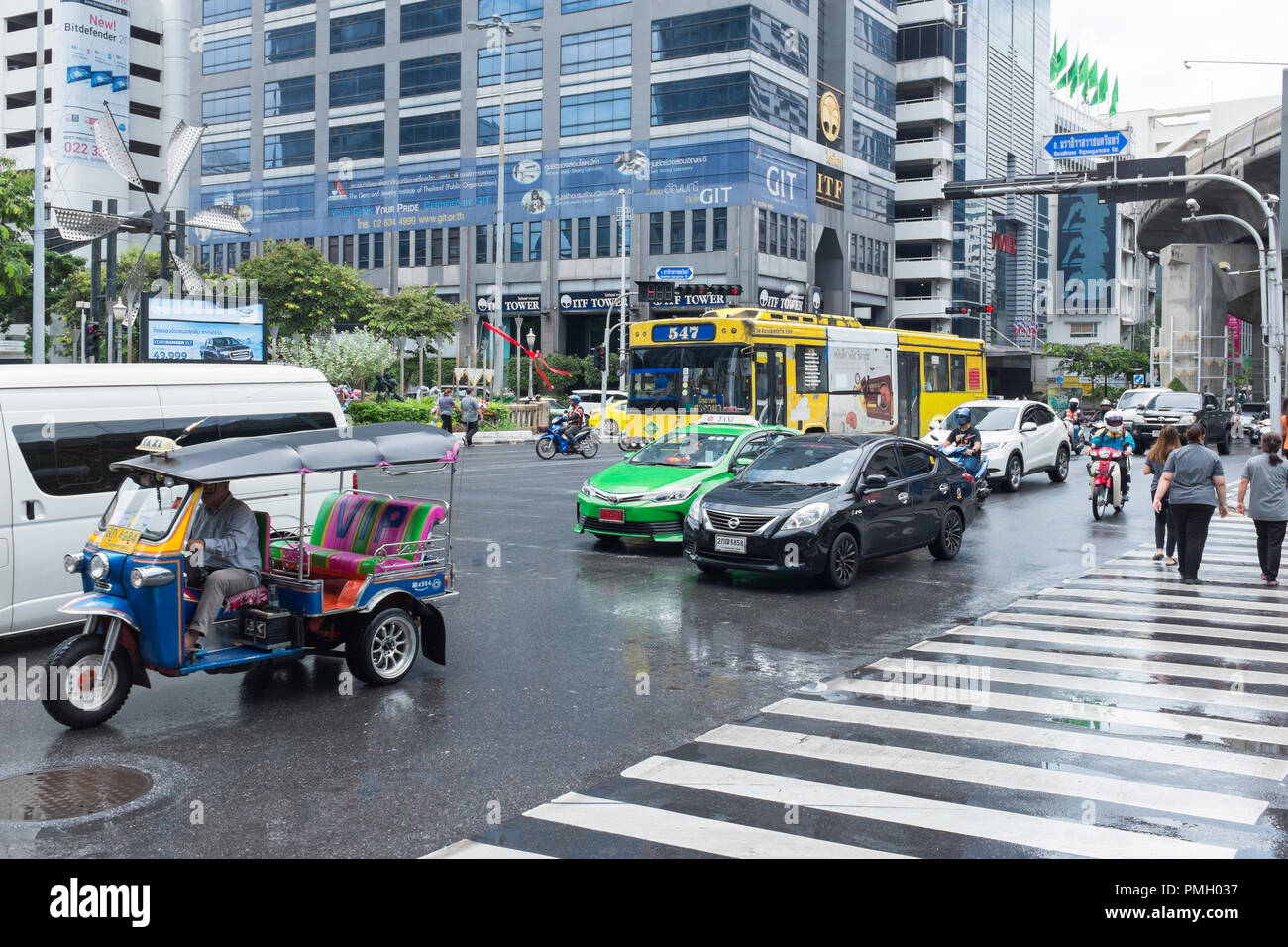 Verkehr, einschließlich einem Tuk Tuk eine nasse Straße im Geschäftsviertel von Bangkok, Thailand Stockfoto