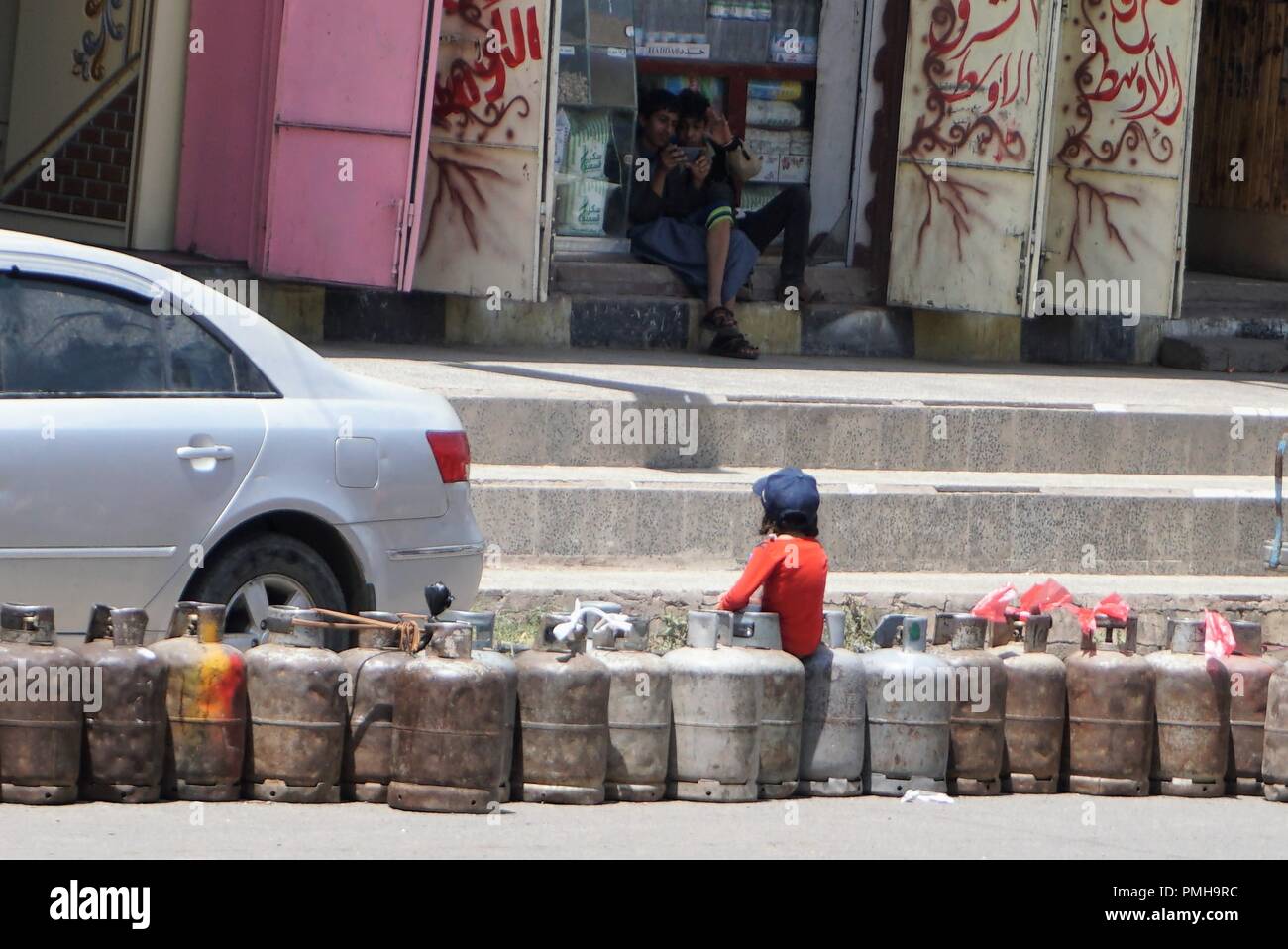 Sanaa, Jemen. 18 Sep, 2018. Ein Kind sitzt auf leere kochen Gasflaschen auf einer Hauptstraße in Sanaa, Jemen, im Sept. 18, 2018. Die Straßen sind fast leer in der jemenitischen Hauptstadt Sanaa eine Woche-lange schwere Brennstoff-mangel Kräfte Hunderttausende Fahrzeuge um die Straßen sterben. Die große Ölkrise wurde durch den eskalierenden Krieg Anfang dieser Woche in strategischen des Landes Rote Meer Hafenstadt Hodeidah nach dem Zusammenbruch der Friedensgespräche, die von den Vereinten Nationen in Genf vermittelt zwischen der Jemenitischen kriegführenden Parteien ausgelöst. Credit: Mohamed al-Azaki/Xinhua/Alamy leben Nachrichten Stockfoto