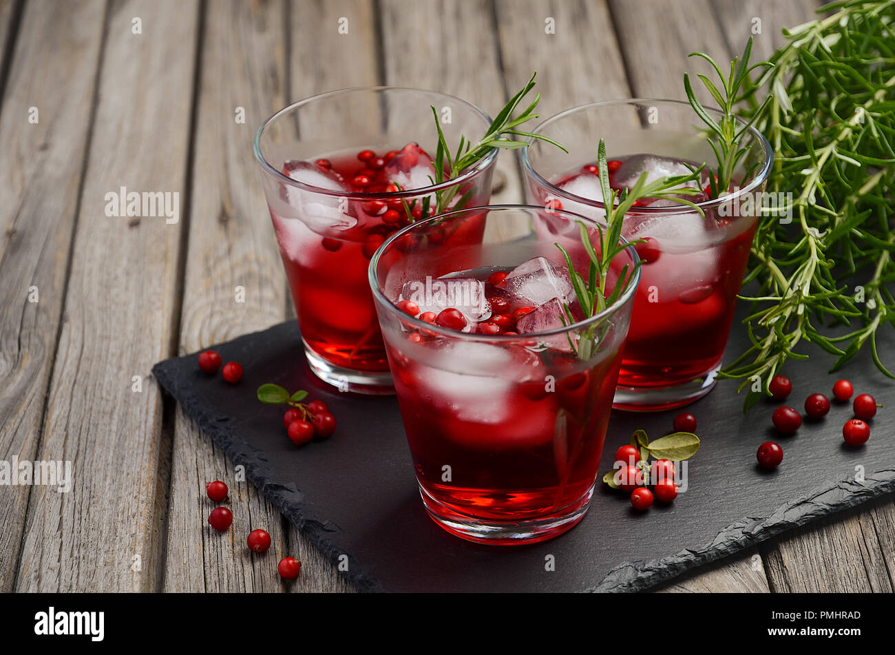 Erfrischendes Getränk mit Preiselbeeren und Rosmarin auf Holz- Hintergrund. Stockfoto