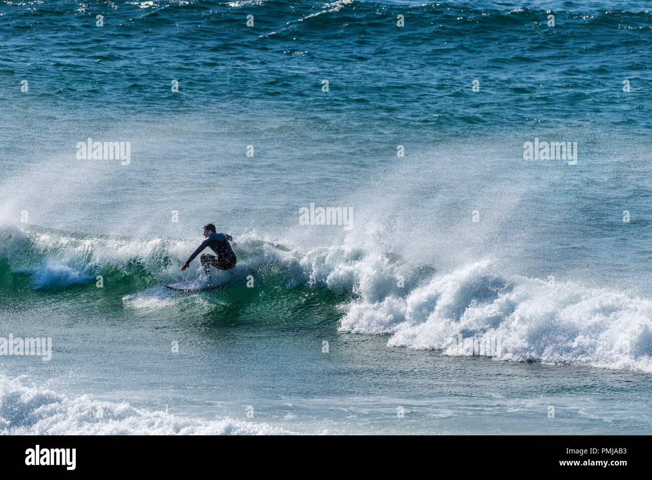 Ein einsamer Surfer an der North Fistral in Newquay in Cornwall. Stockfoto