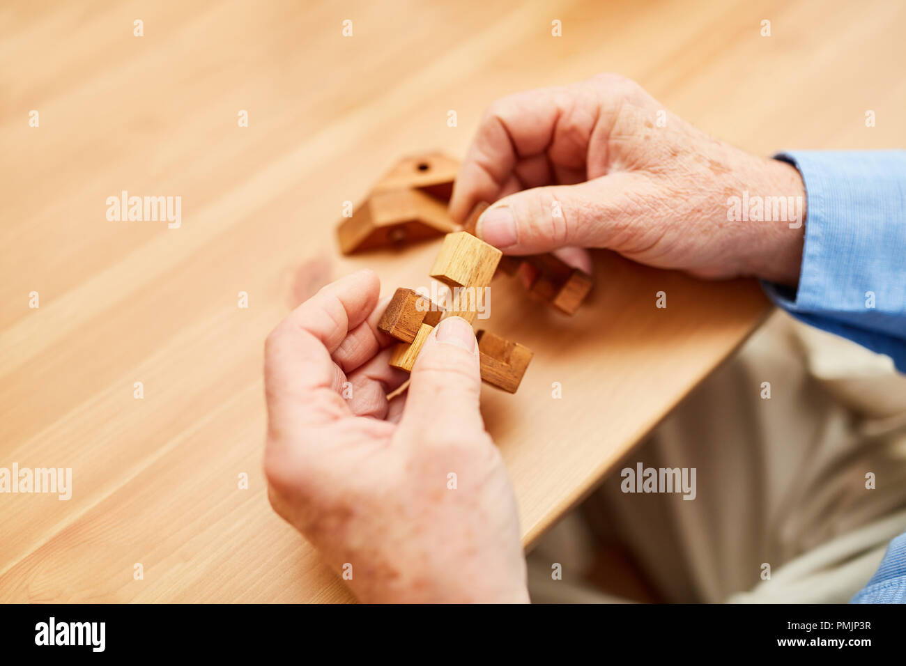 Die Hände eines alten Mannes, Holz- Bausteine zusammen als Geduld Spiel Stockfoto