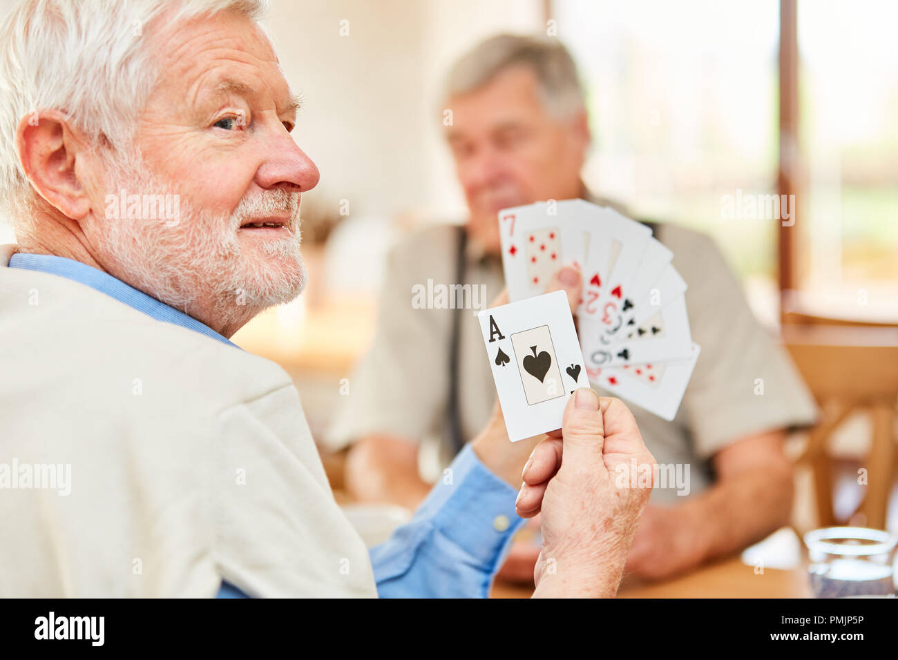 Senior zeigt ein Trumpf im Kartenspiel Turnier im Altenheim oder zu Hause Stockfoto