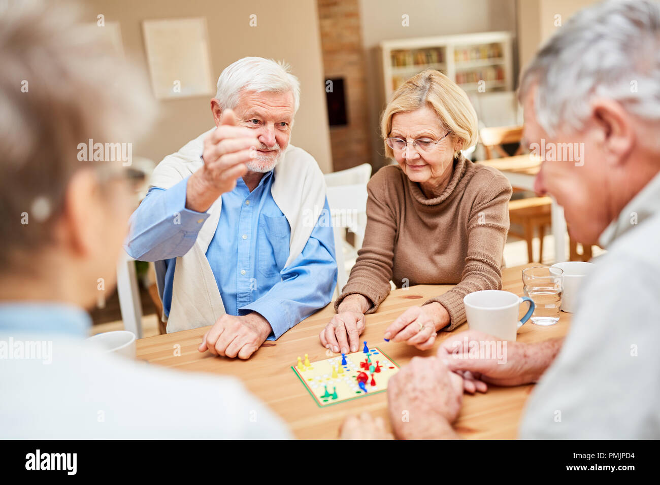 Senioren als rentnerehepaar spielt mit Freunden ein Brettspiel im Altenheim oder zu Hause Stockfoto