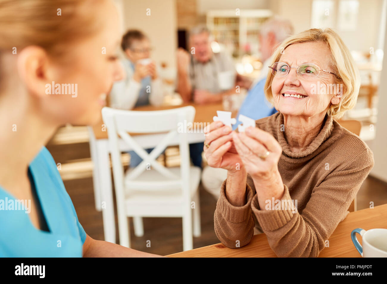 Ältere Frau und eine Altenpflegerin in Demenz Therapie beim Spielen Puzzle Stockfoto
