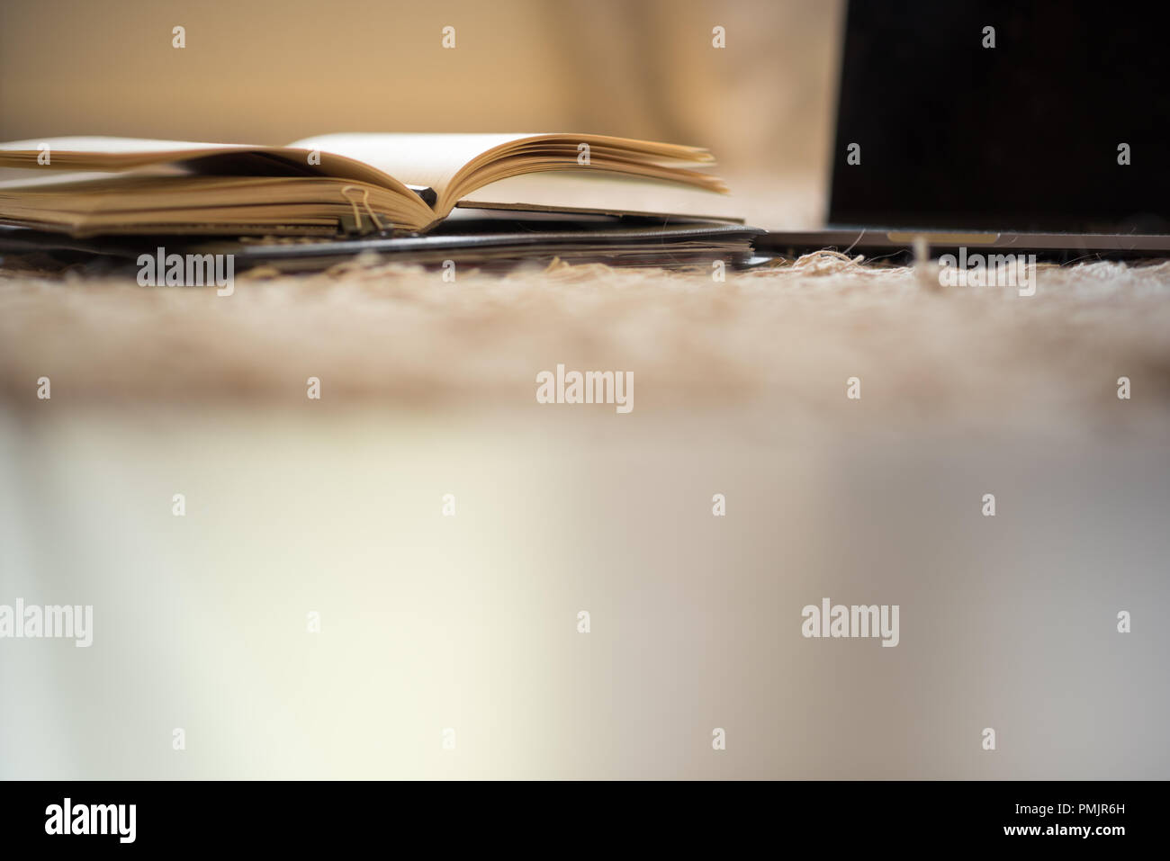 Eine abstrakte low-winkel Betrachten der Seiten eines offenen Journal neben einem offenen Laptop, mit einem großen Bereich für Kopie am unteren Stockfoto