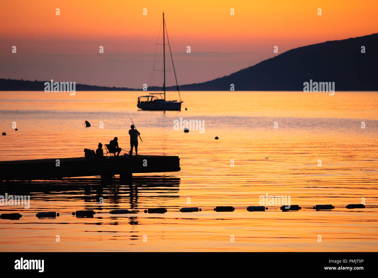 Silhouette von Menschen Angeln auf dem Meer bei Sonnenuntergang. Schöne Meer Sonnenuntergang Szene. Stockfoto