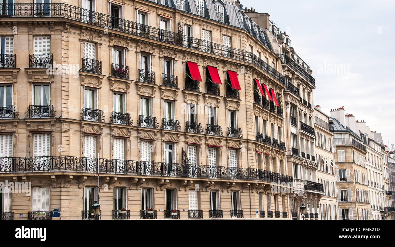 Roten Markisen Abdeckung Windows auf einem typischen Pariser Gebäude mit schwarzen schmiedeeisernen Geländer. Stockfoto
