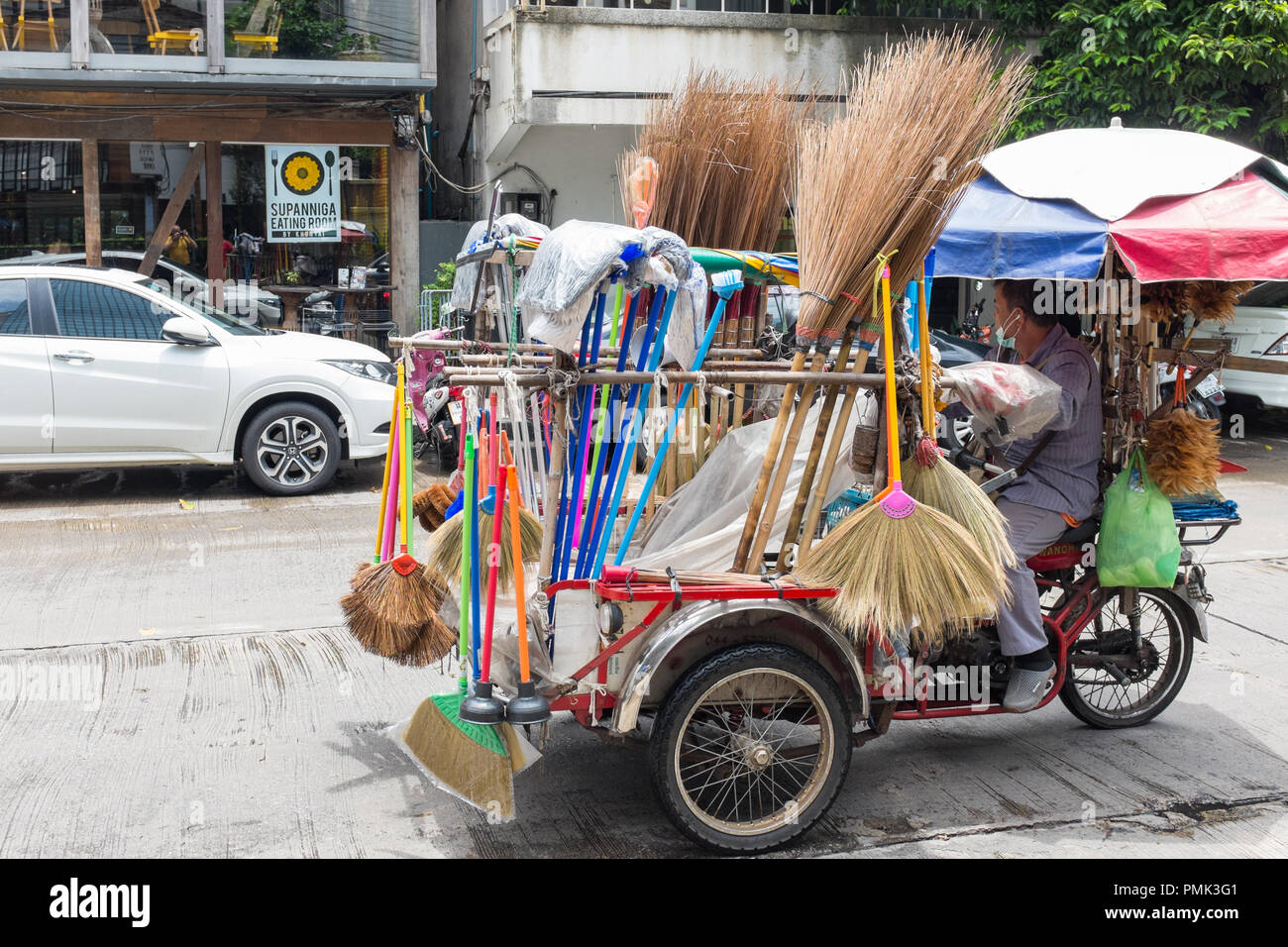 Street Hersteller Verkauf von Bürsten, Besen und Stimmung aus einem Pedal powered Tricycle in Bangkok, Thailand Stockfoto