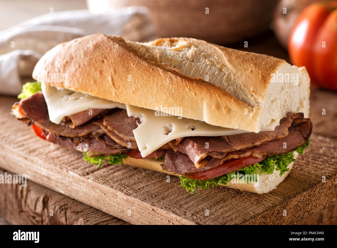 Eine köstliche Roastbeef Sandwich mit Käse, Salat und Tomaten auf einer französischen Brot Baguette. Stockfoto