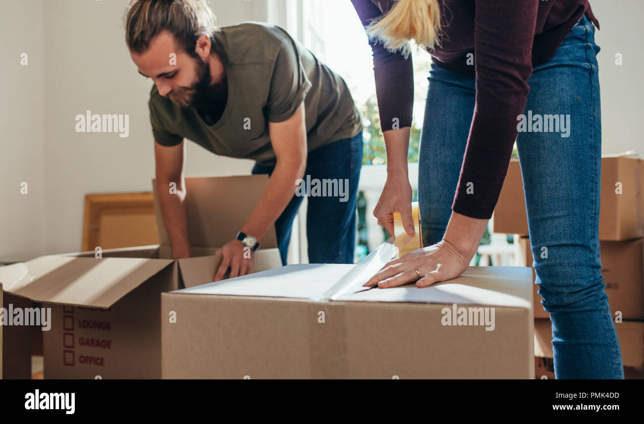 Paar packen Ihren Haushalt Artikel in Kisten packen. Frau ein Klebeband auf  einen Karton während ein Mann füllt Reihen in einen Karton Stockfotografie  - Alamy
