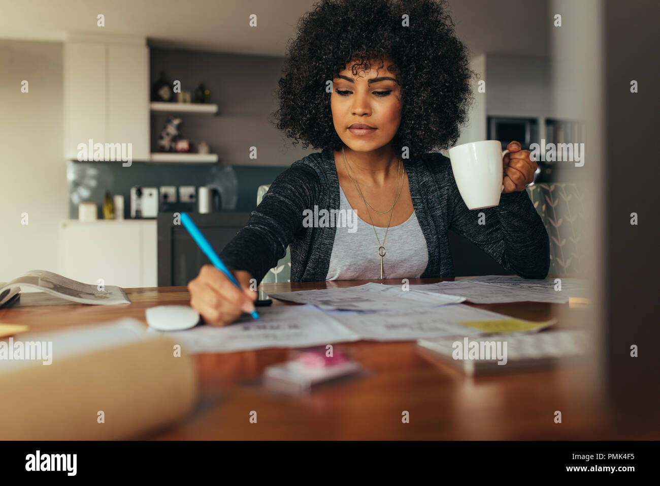 Weibliche Architekt einen Projektplan mit Tasse Kaffee in der Hand. Innenarchitekt Korrektur einer Zeichnung während zu Hause Büro zu sitzen. Stockfoto