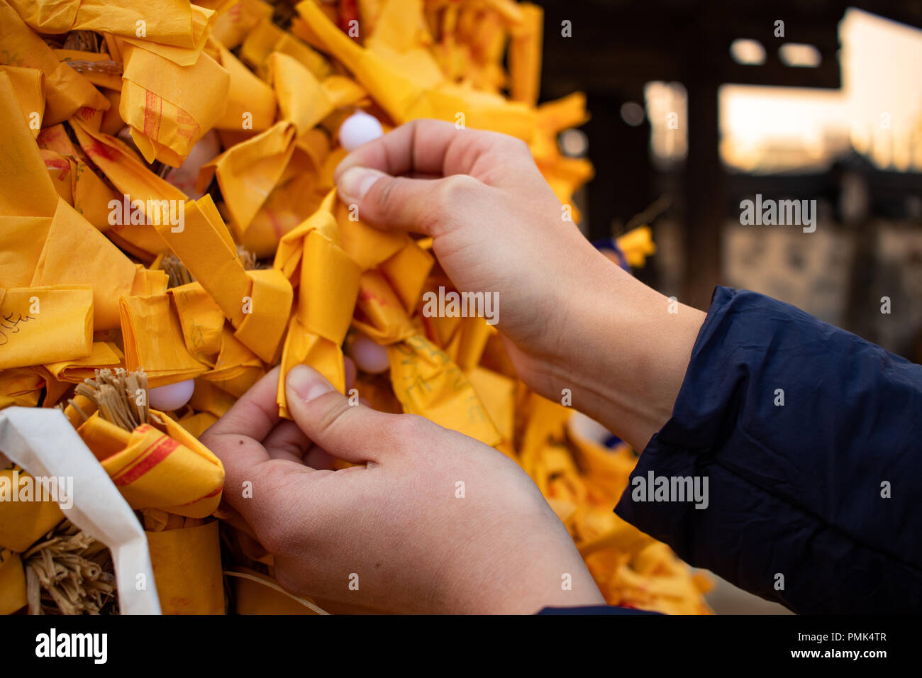 Mädchen Hände Anpassung Glück gelbes Papier Knoten auf asiatischen Tempel Stockfoto