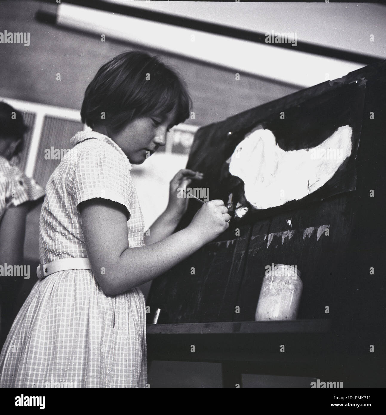 1960er Jahre, junge Schulmädchen in einem clasroom stehen eine Staffelei malen ein Bild, ein Aquarell, England, UK. Stockfoto