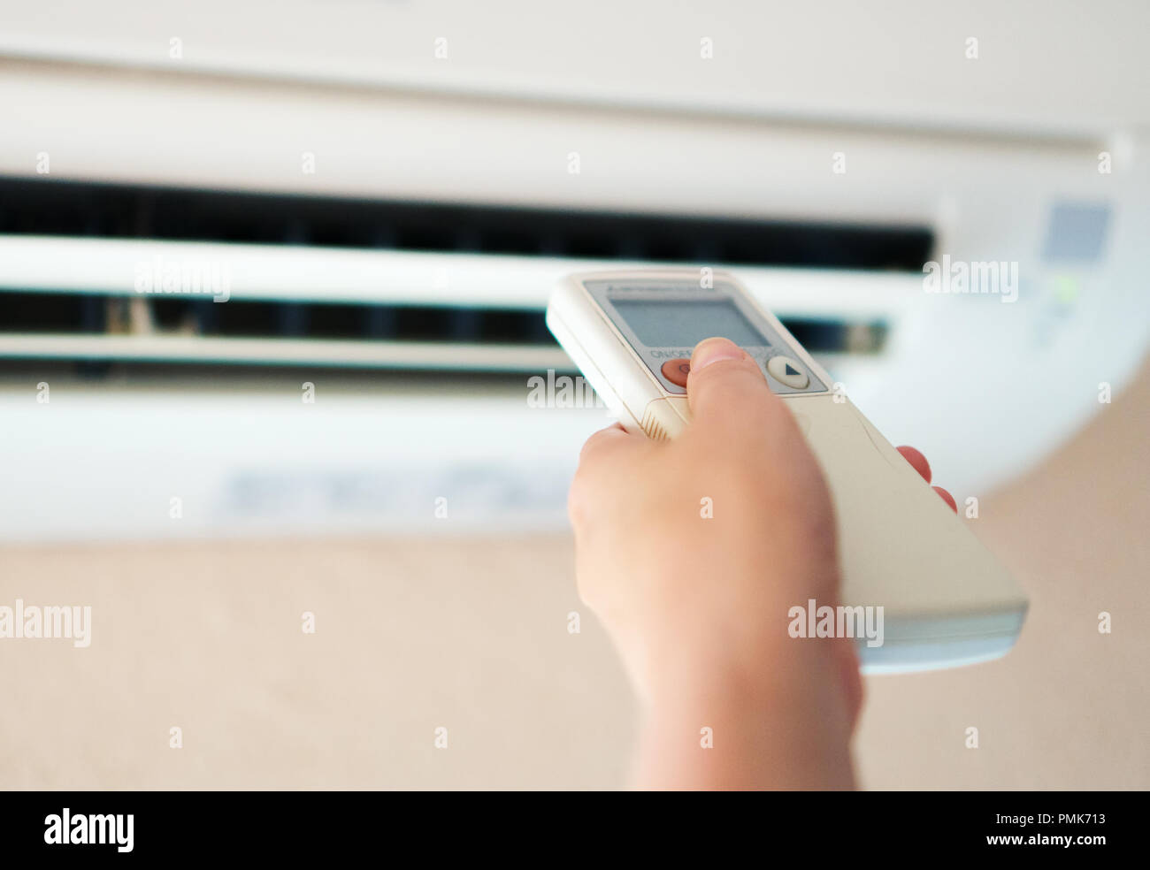 Hand, die Fernbedienung auf die Klimaanlage. Stockfoto