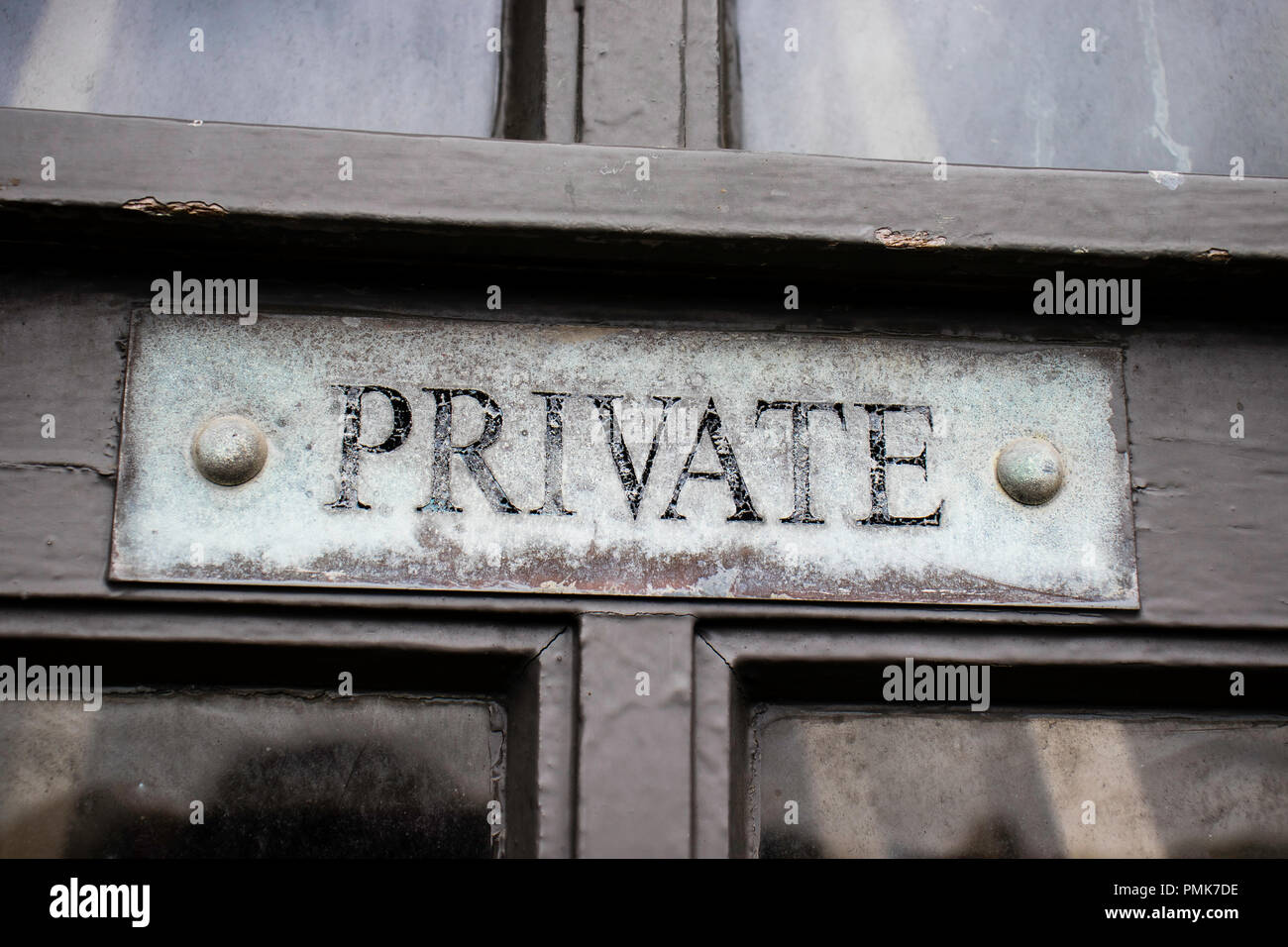 Alte, verwitterte private Zeichen auf hölzernen Tür Stockfoto