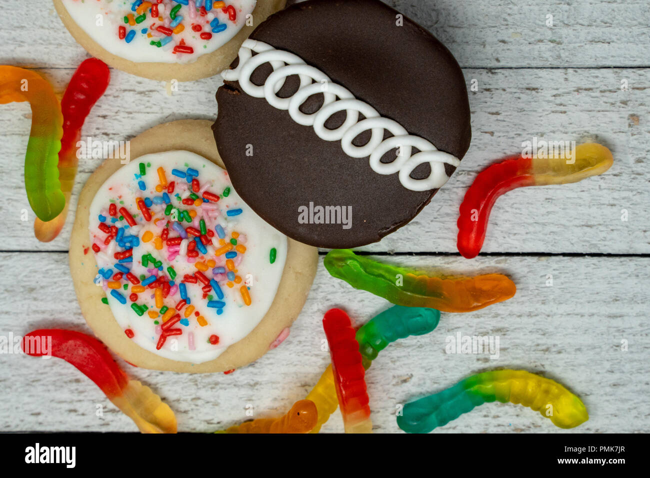 Schokolade Kuchen, Eis frosted Sugar Cookies mit Streuseln und Gummibärchen Würmer auf Holz- Hintergrund Stockfoto