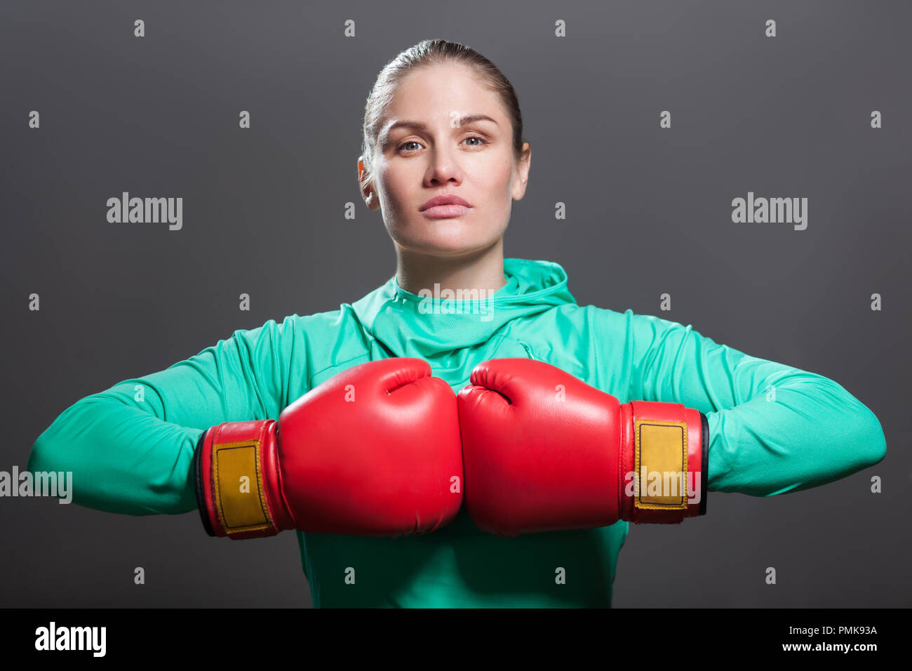 Ernsthafte zuversichtlich, schöne junge Athlet Frau mit gesammelten Haare stehen in der Position in der oberen Arme, Hände zusammen im Boxen rote Handschuhe. Stockfoto