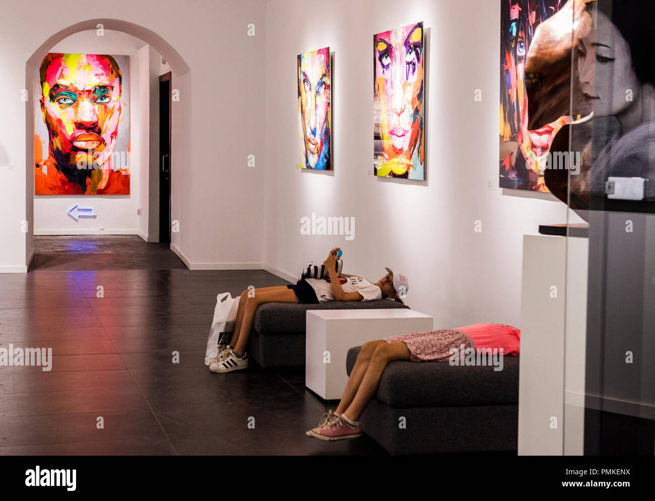 Zwei junge Frauen, liegen auf Sitzen, die in der Galerie, die von Kunstwerken, Barcelona, Spanien umgeben, Europa Stockfoto