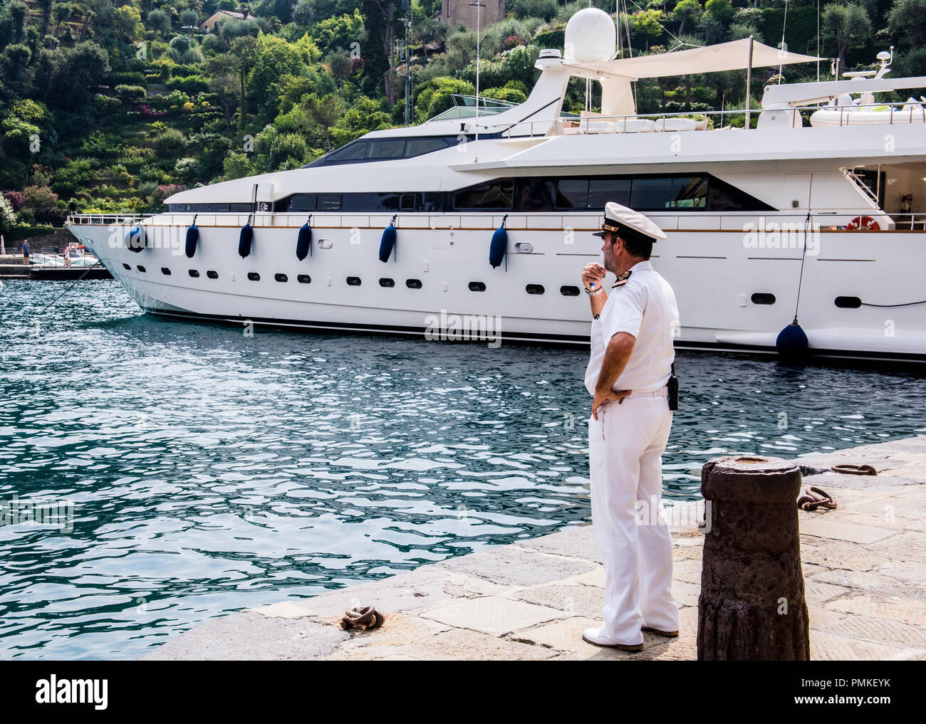 Italienischer Marineoffizier mit einem nachdenklichen Ausdruck, in Port, luxuriöse Yacht im Hintergrund stehend, Portofina, Genua, Italien, Europa Stockfoto