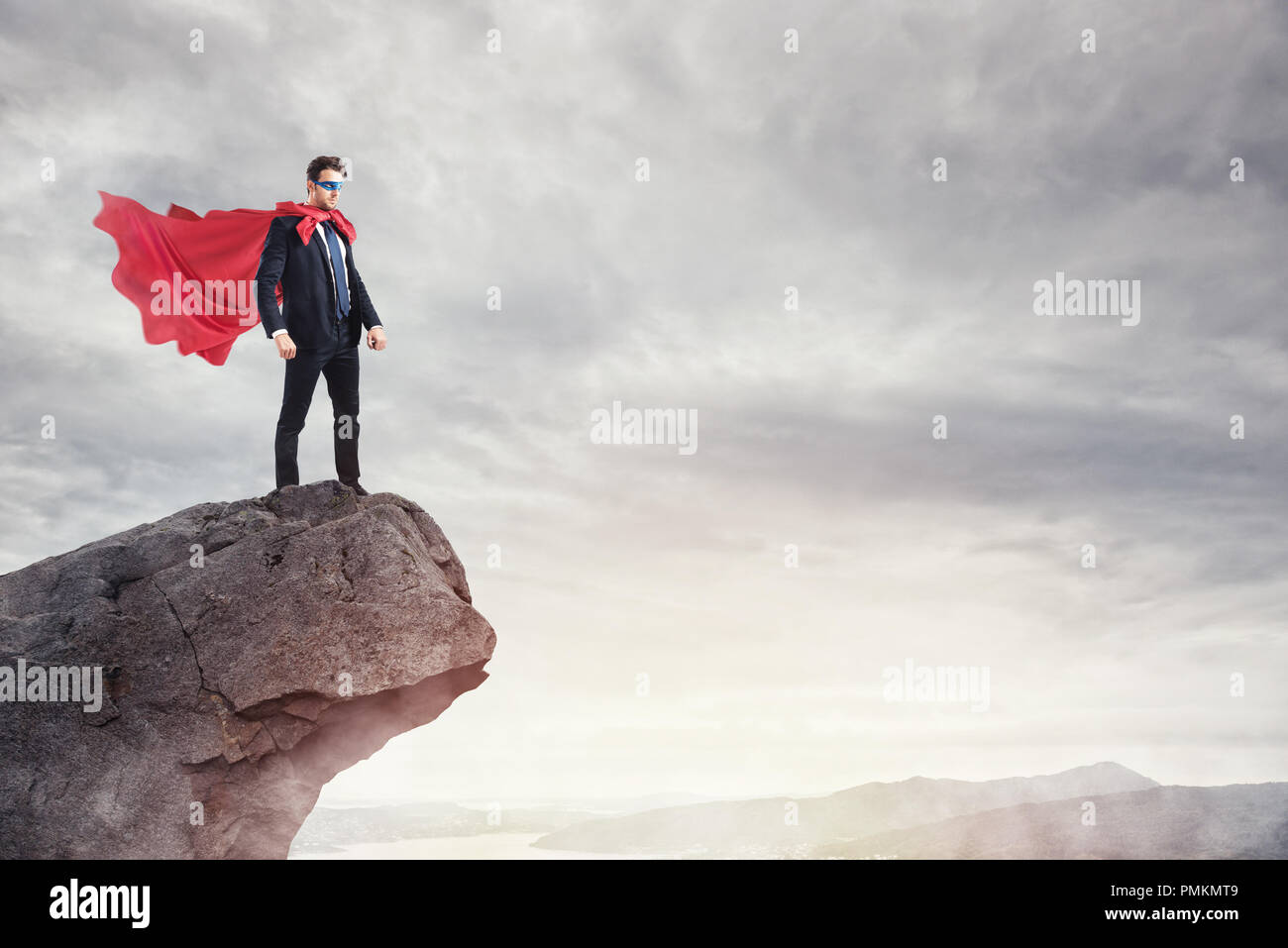 Geschäftsmann als Super Hero auf dem Gipfel eines Berges Stockfoto