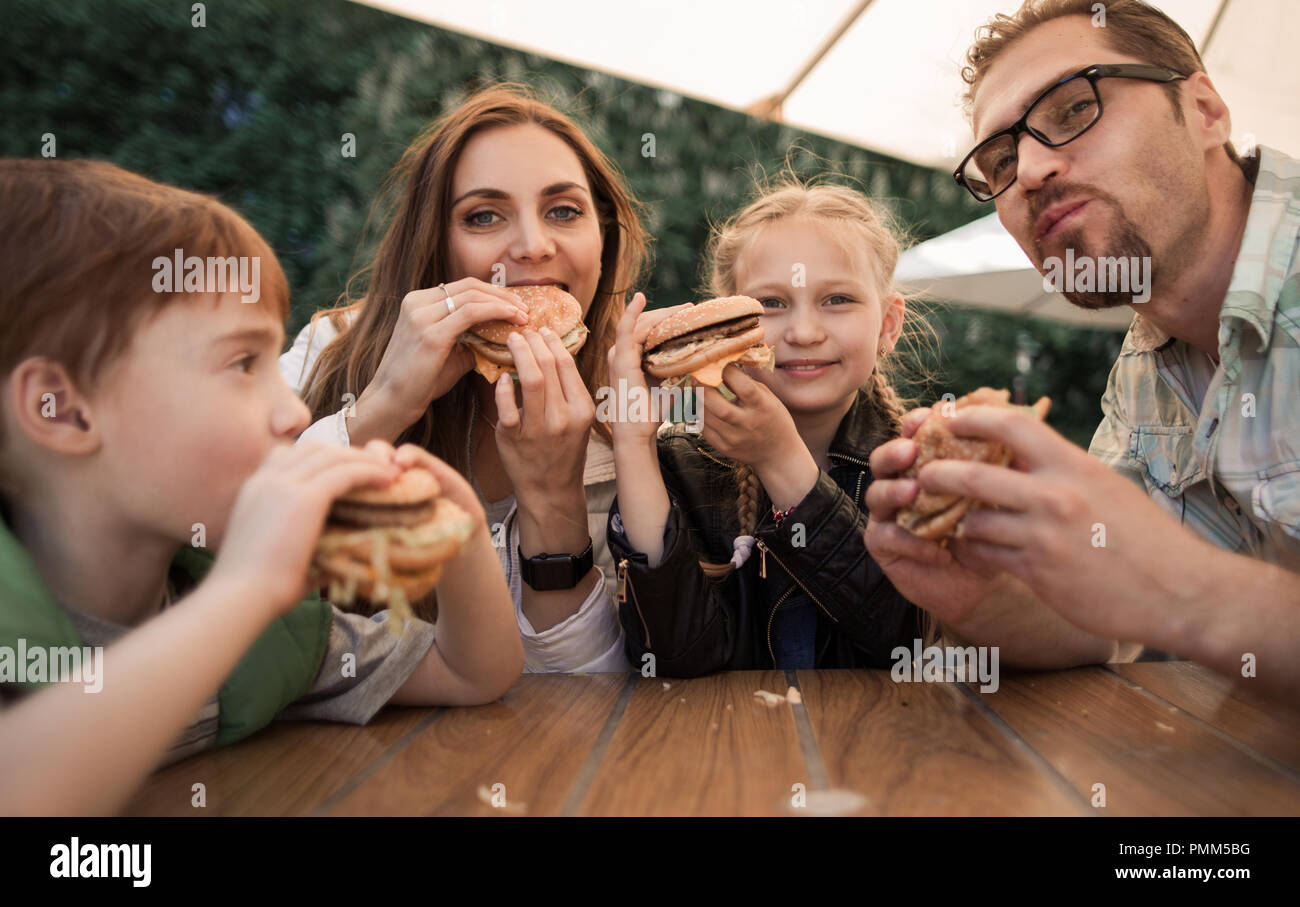 Glückliche Familie Burger essen an einem Tisch sitzen in einem Cafe Stockfoto