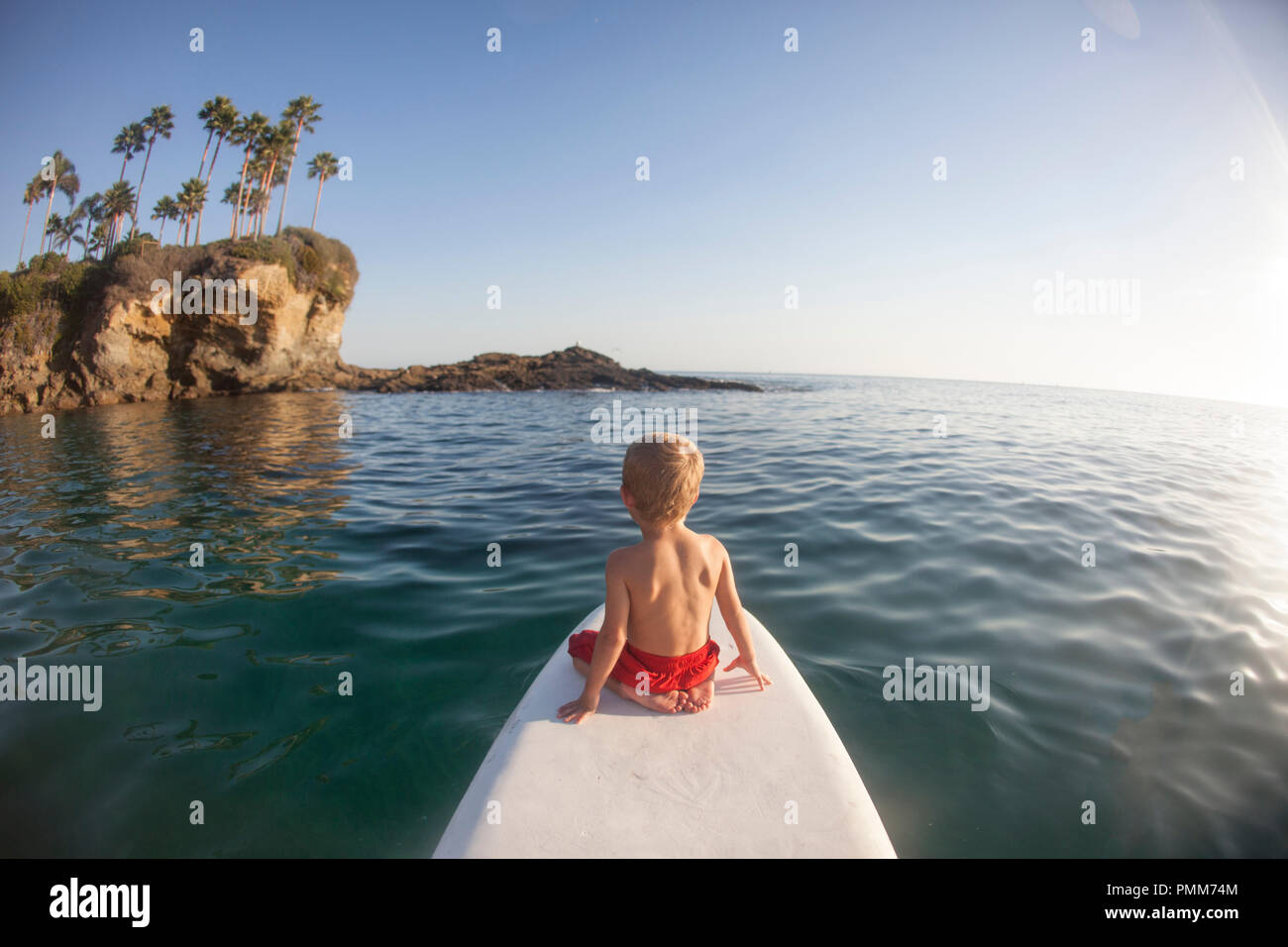 Junge sitzt auf einem paddleboard, Orange County, Kalifornien, USA Stockfoto