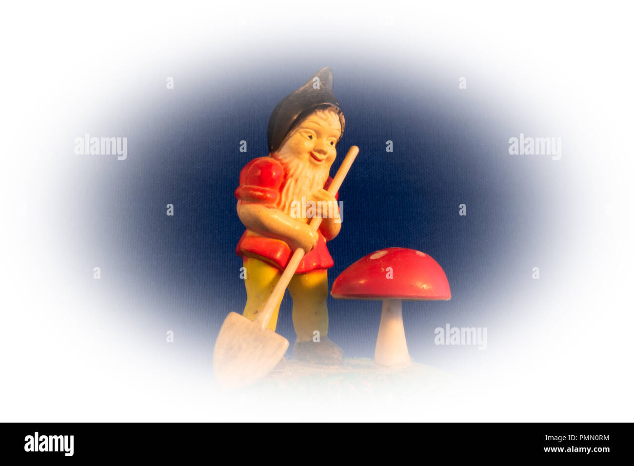 In der Nähe des Miniatur vintage Gartenarbeit gnome mit einer kleinen Schaufel und rote Gift Fliegenpilz, Pilz auf Vignette Hintergrund Stockfoto