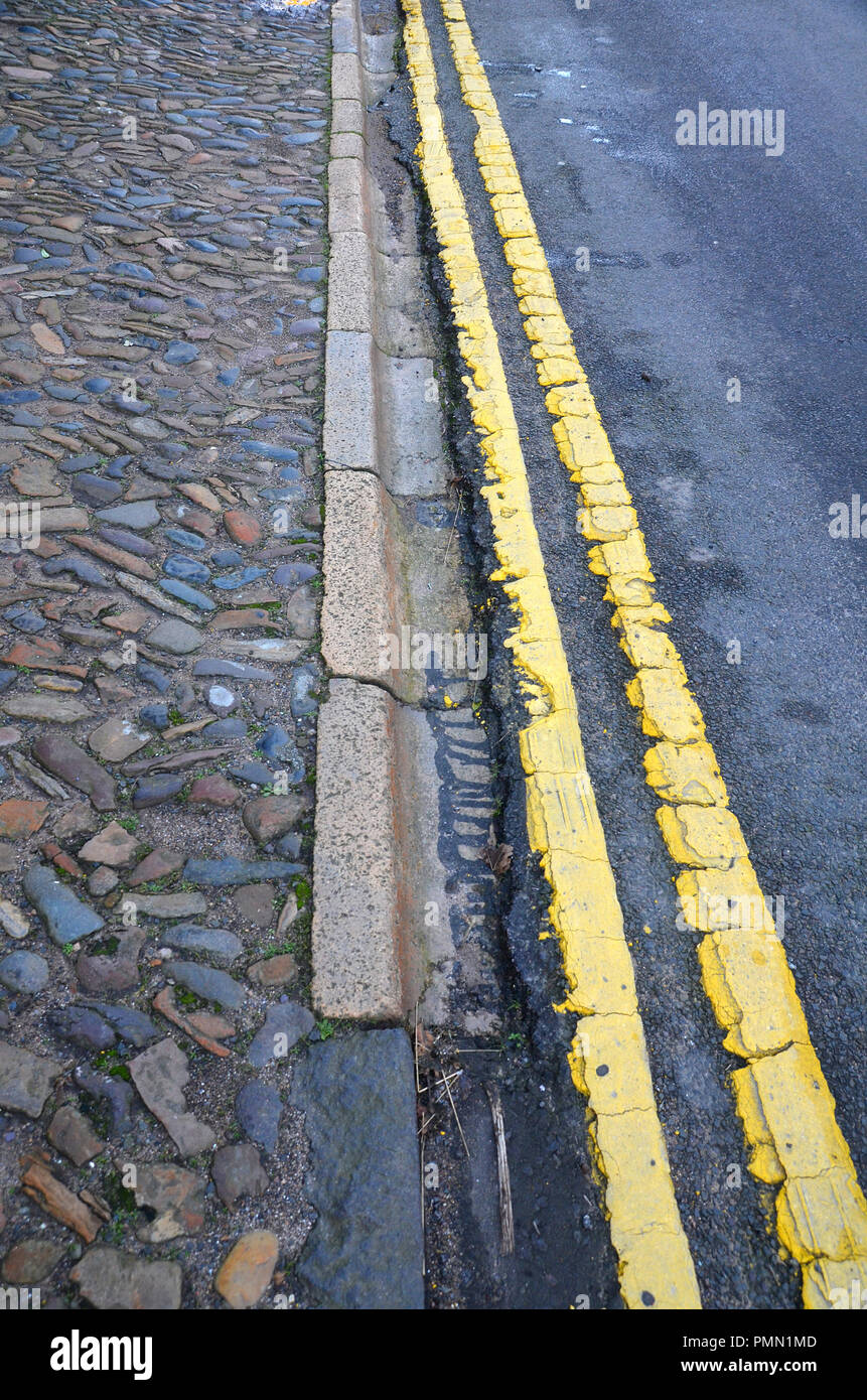 Nahaufnahme des gepflasterten Gehweg, Straße Dachrinne und Asphalt und gelb lackiert Double Line. Stockfoto