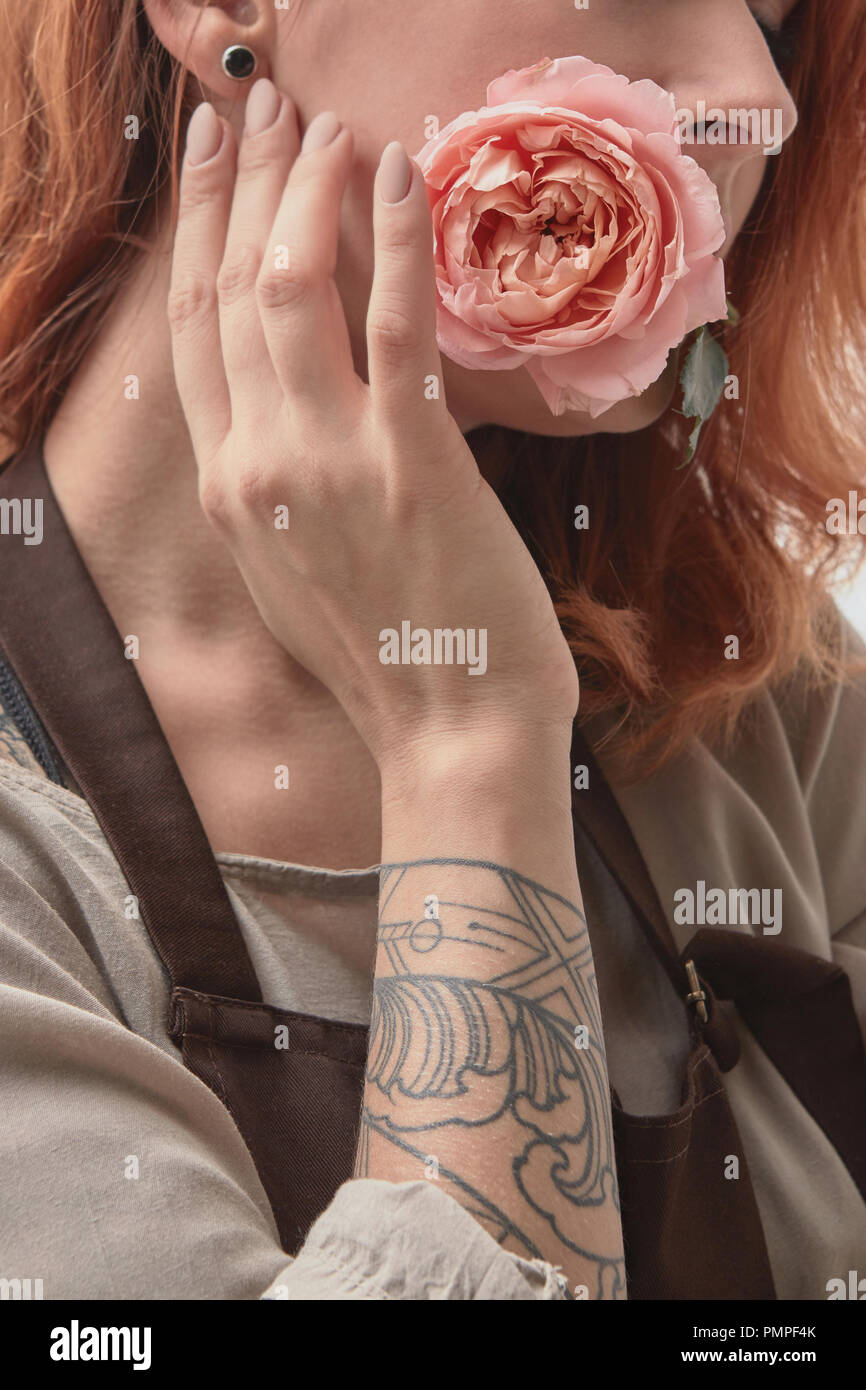 Das Rothaarige Madchen Mit Einem Tattoo Halt Eine Rosa Rose In Ihrem Mund Layout Fur Postkarte Stockfotografie Alamy