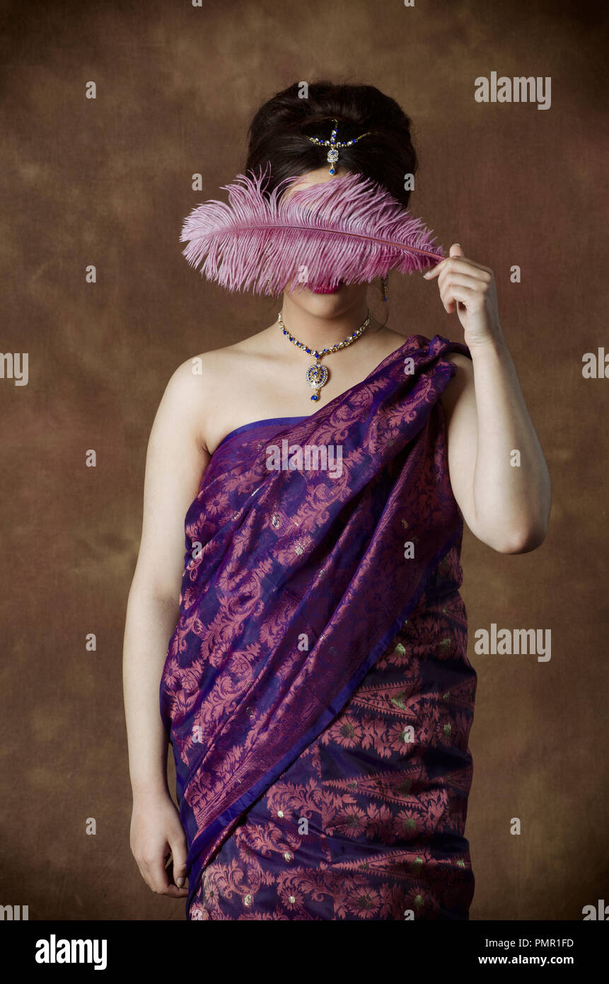 Indische Frau verstecken Gesicht mit einem rosa Feder Stockfoto