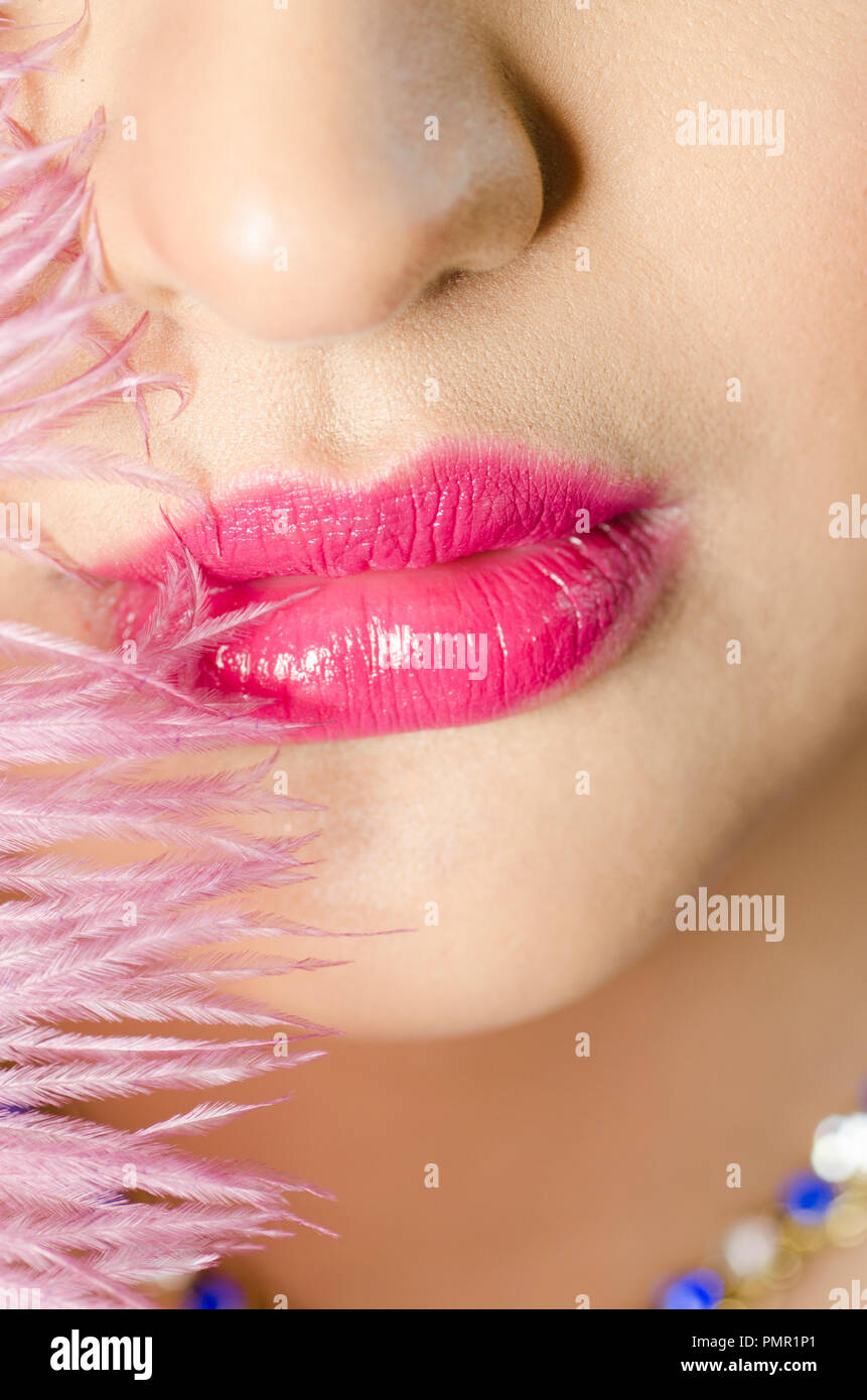 Nahaufnahme der Lippen der Frau mit roten Lippenstift und rosa Feder Stockfoto