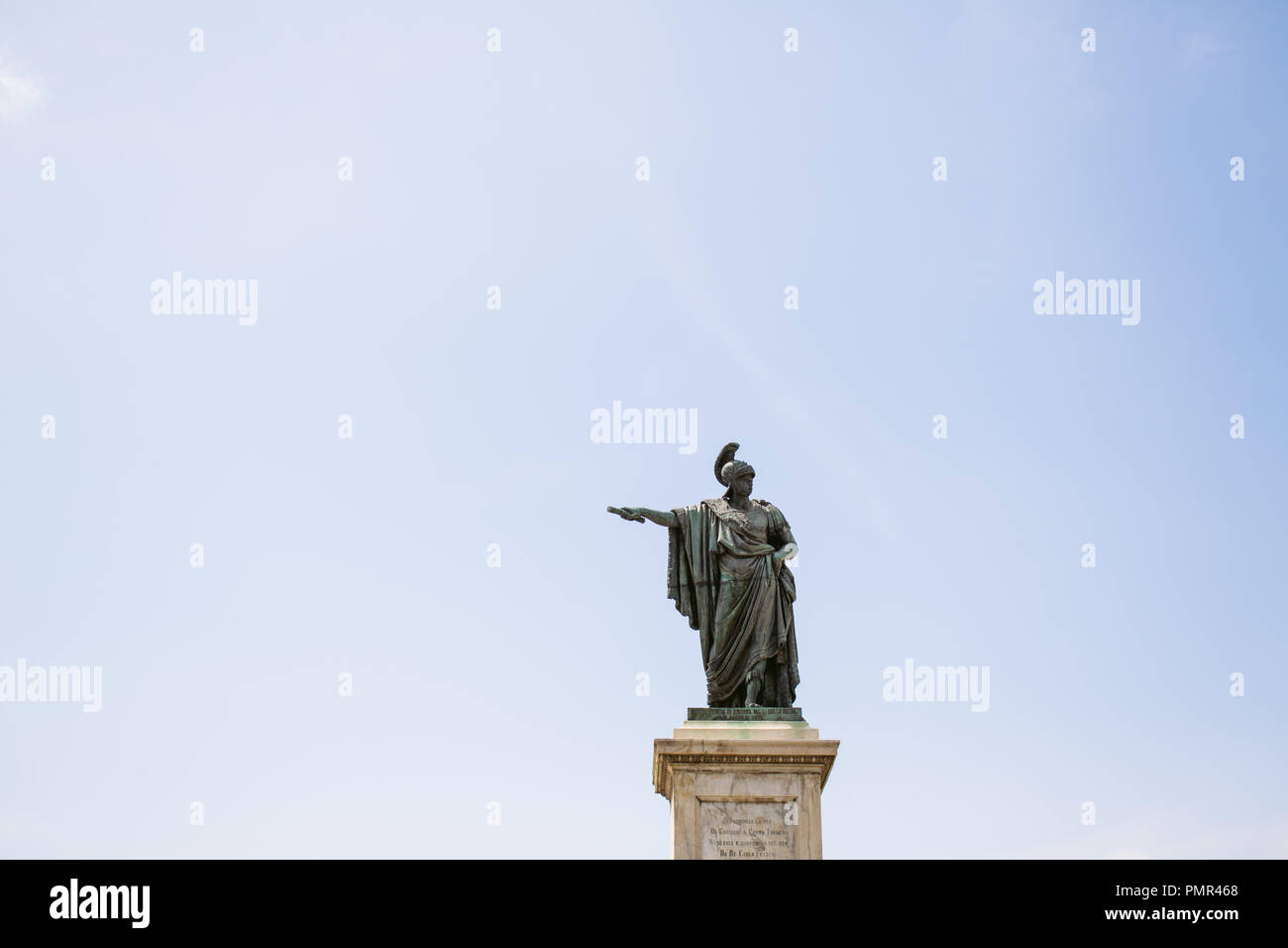 Statue einer römischen Zenturio oder Kaiser Holding eine Rolle und zeigt auf der linken Seite des Rahmens (Recht der Statue) gegen einen leeren blauen Himmel mit Kopie Raum Stockfoto