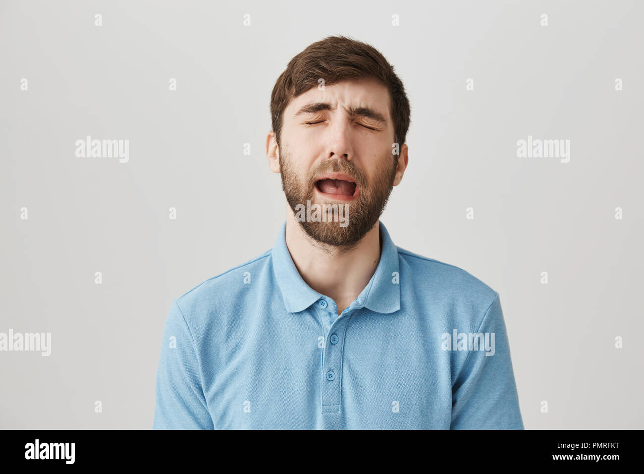 Taille-up Shot aufgeregt stattlichen kaukasischen Kerl in Shirt, Heulen oder weinen, als ob er Baby, stehend über grauen Hintergrund. Frau Passwort auf Laptop, also kann er nicht spielen, bis er Wäsche fertig stellen Stockfoto