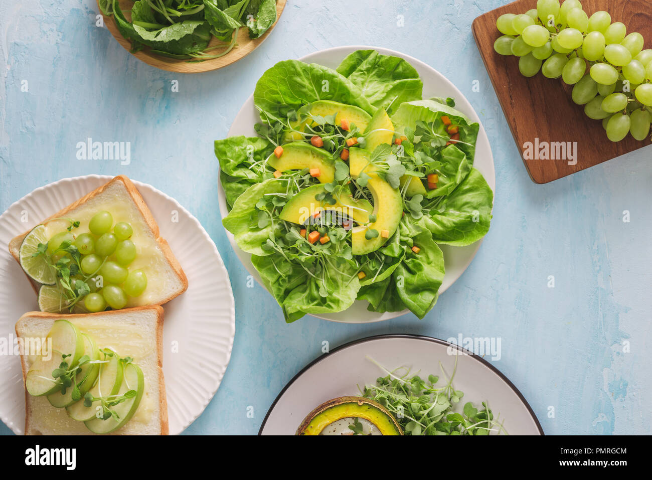 Gesunde vegane Frühstück. Ernährung. Gebackene Avocado mit Ei und frischem Salat aus Rucola, Toast und Butter. Auf eine weiße Marmorplatte, einem konkreten Leuchttisch. Stockfoto