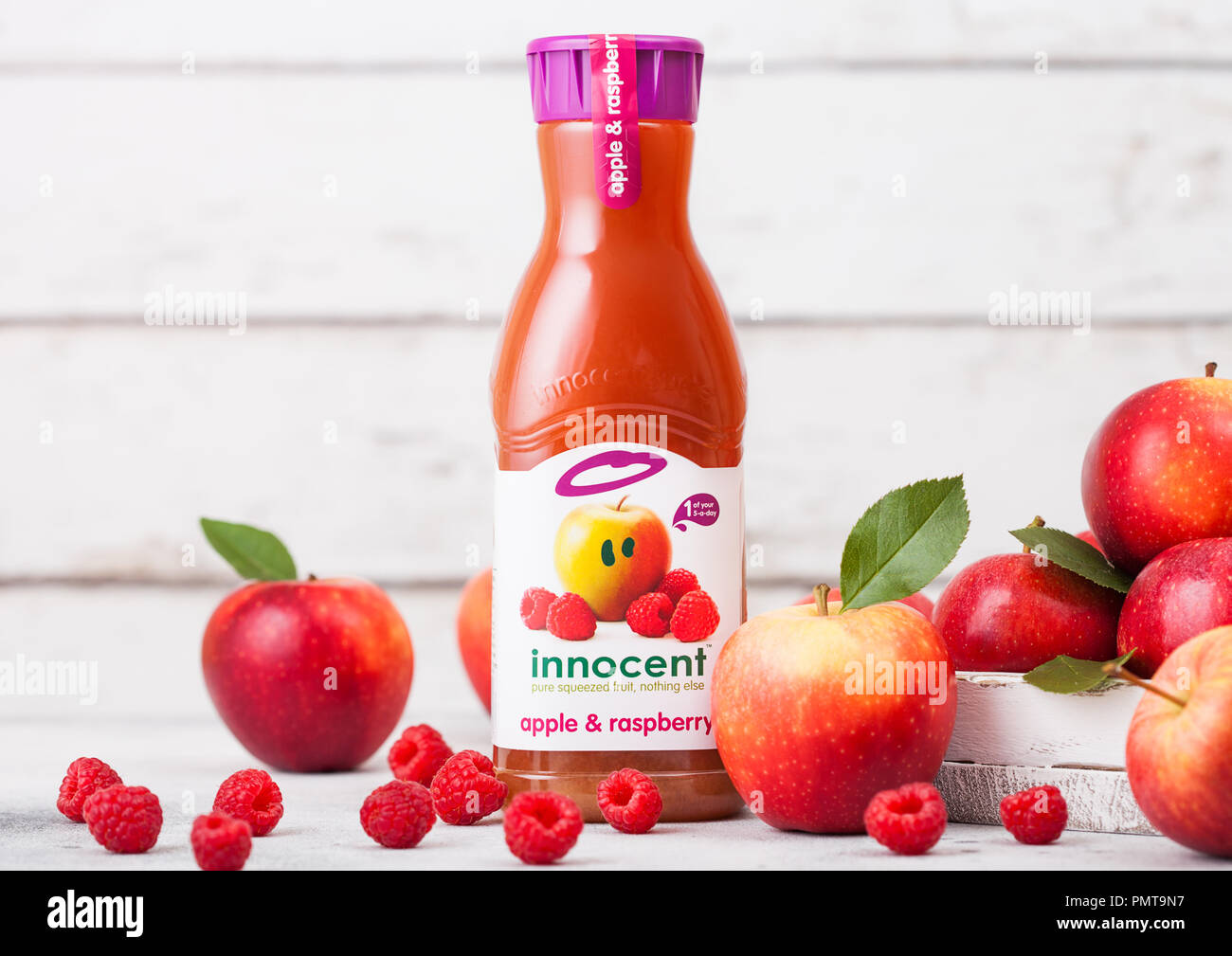 LONDON, Großbritannien - 13 September, 2018: Kunststoff Flasche frisches Unschuldigen Apfel- und Himbeersaft mit frischen Äpfeln in Feld auf Holz Hintergrund. Stockfoto