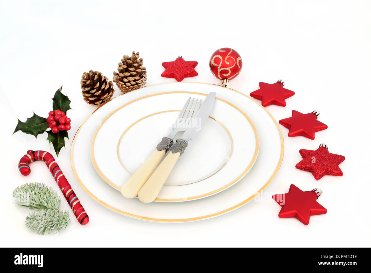 Weihnachtsessen Tabelle Ambiente mit weißen Porzellan Teller, Besteck, Christbaumkugel Dekorationen und Winter Stechpalme und Tanne auf weißem Hintergrund. Stockfoto