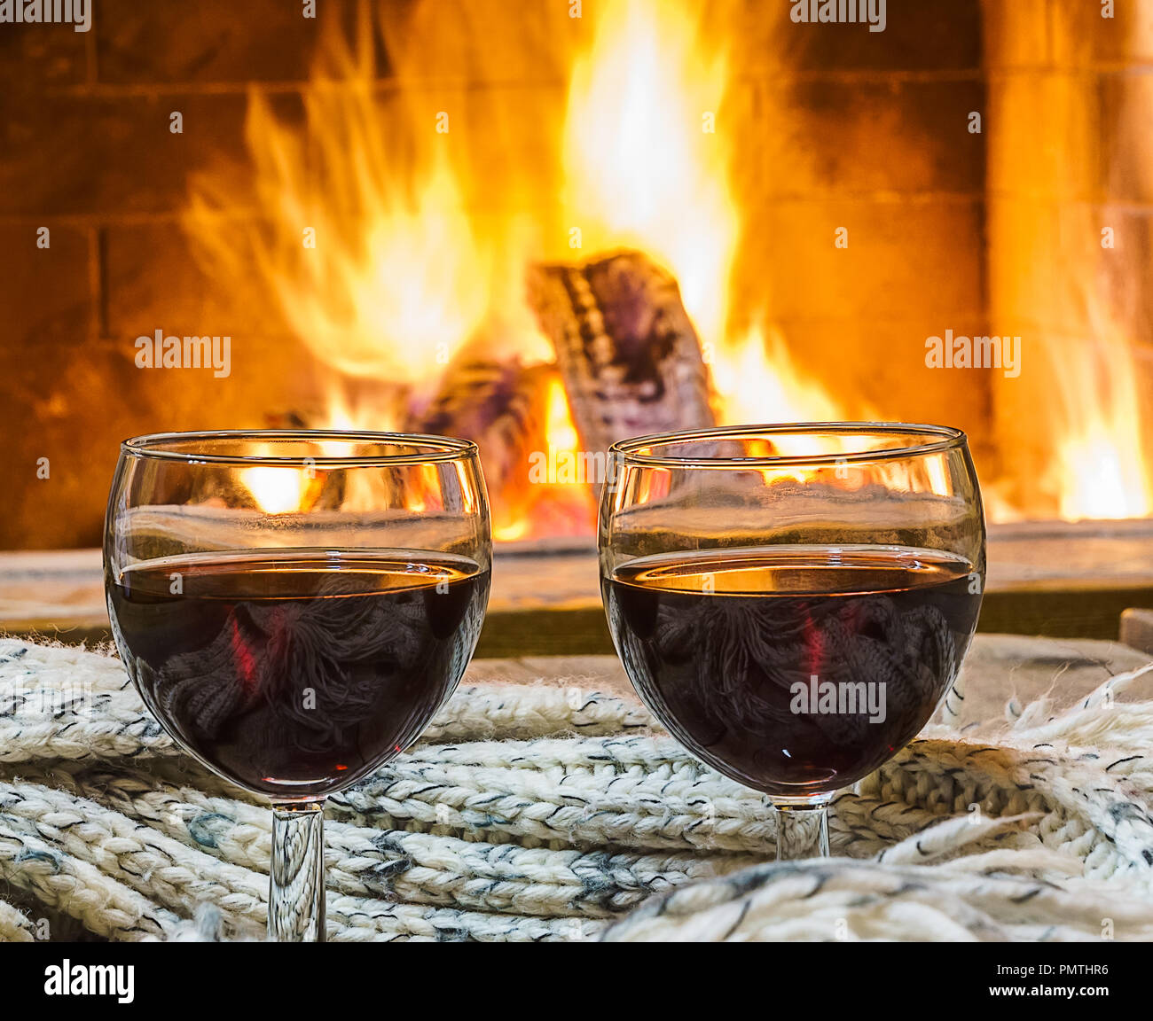 Rotwein in einer Brille mit Wolle Dinge, vor dem gemütlichen Kamin Hintergrund, in Country House, Weihnachten Winter Urlaub. Stockfoto