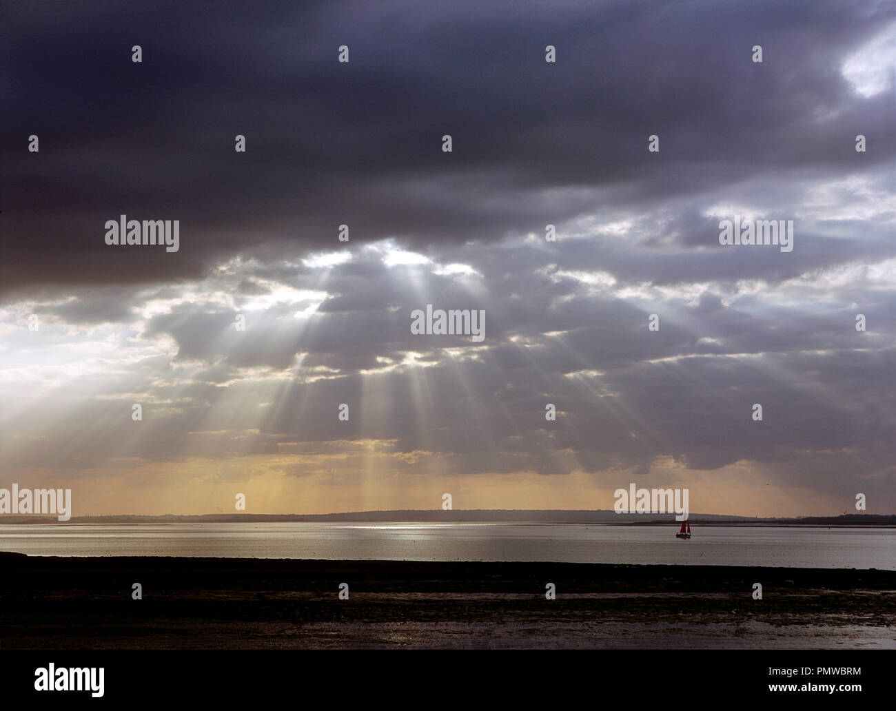 Sonnenlicht-streaming durch dunkle Gewitterwolken über dem Fluss Blackwater in der Nähe von Bradwell Waterside in Essex. Stockfoto