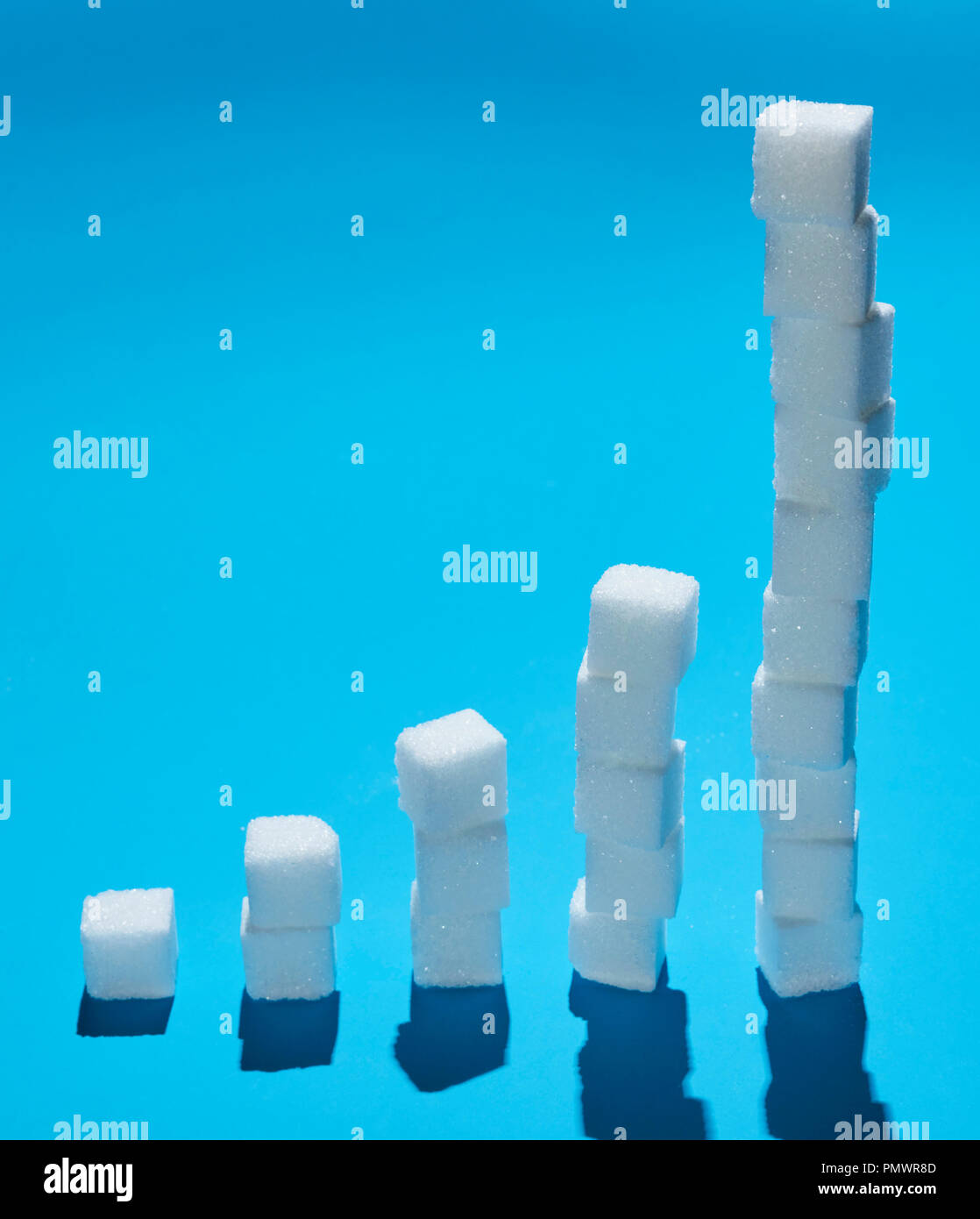 Würfel Zucker bilden ansteigendes Leuchtband auf blauem Hintergrund Stockfoto