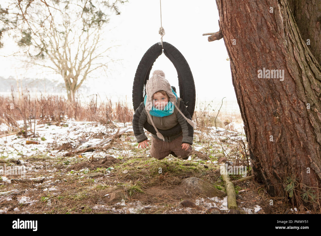 Süße Mädchen spielen in reifen Schwingen in der verschneiten Hof Stockfoto