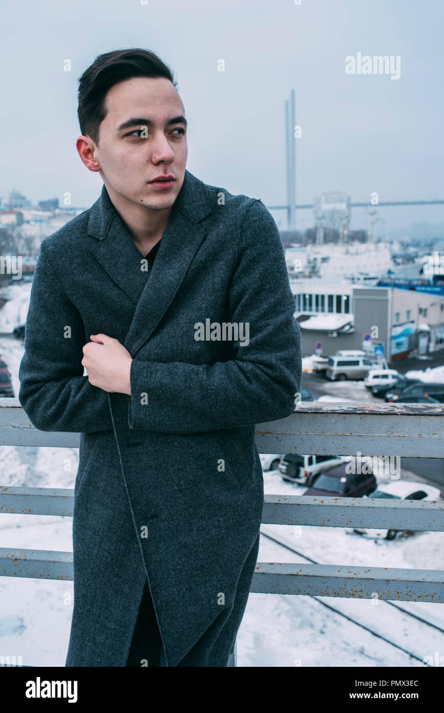 Junger Mann in langen Mantel auf Urban Winter Brücke Stockfoto