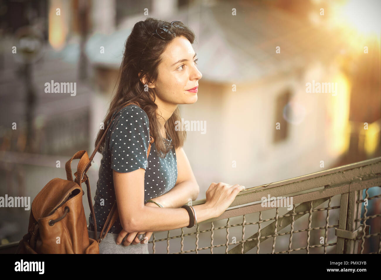 Kontemplative junge Frau lehnte sich auf einem Geländer Stockfoto