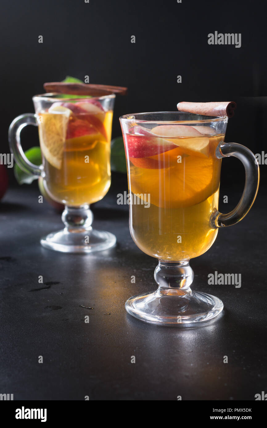 Glas Tee mit Zitrone, gewürzt, in Scheiben geschnittenen Apfel und Zimt auf dem Schwarzen Brett. Close Up. Herbst noch leben. Stockfoto