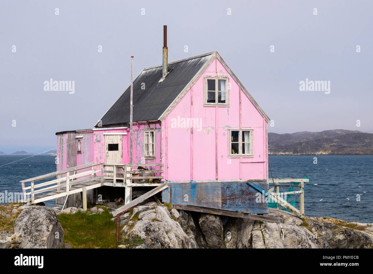 Typische Inuit Holzhaus lackiert rosa mit Fischernetze trocknen außerhalb. Itilleq, Qeqqata, Grönland. Auf einer kleinen Insel 2 km nördlich des Polarkreises Stockfoto