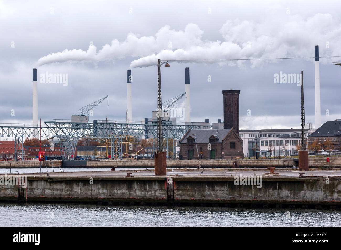 Amager Bakke Waste-to-energy Plant vier Schornsteine mit Rauch und einen alten Hafen Gebäude, Kopenhagen, Dänemark Stockfoto