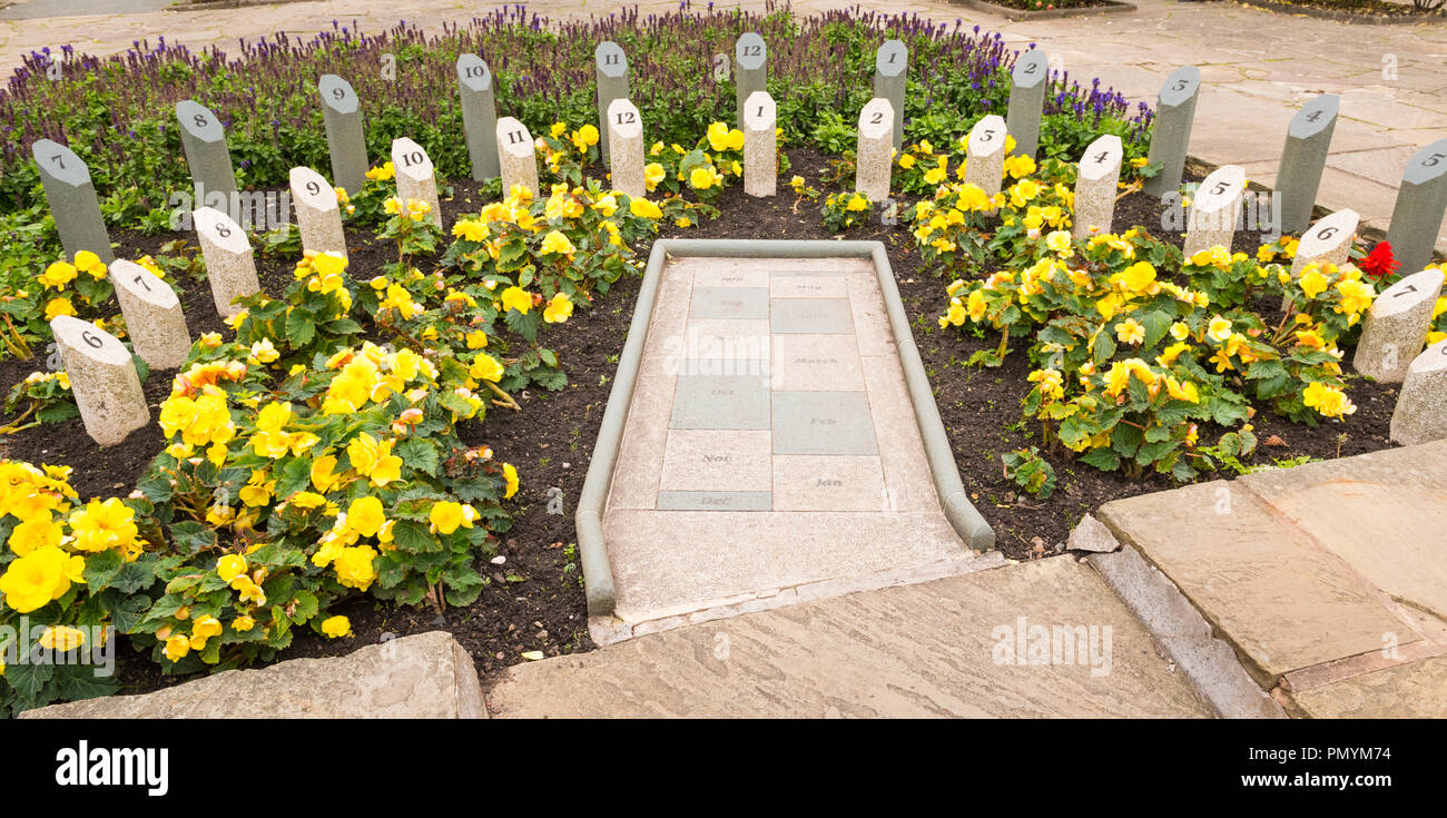 Liverpool Wirral Port Sunlight Village Gardens Park Analemmatic Sonnenuhr horizontal Diamond Jubilee Sonnenuhr 2012 Gelbe Blumen person Schatten gnomon Stockfoto